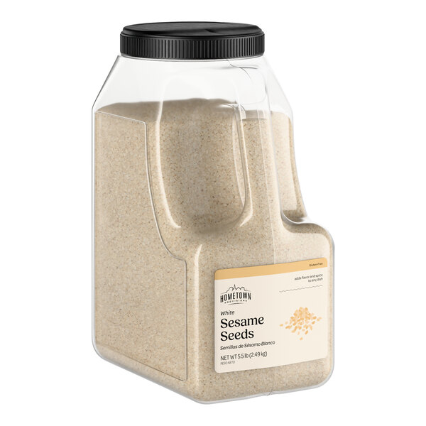 A large plastic container of Hometown Provisions white sesame seeds.