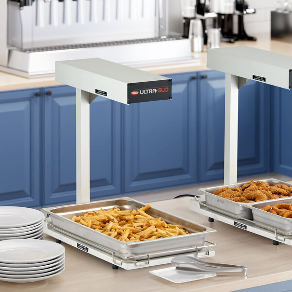 A Hatco Ultra-Glo portable food warmer with two trays of food on a counter.