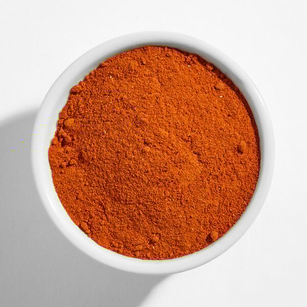A white bowl filled with finely ground red paprika powder.