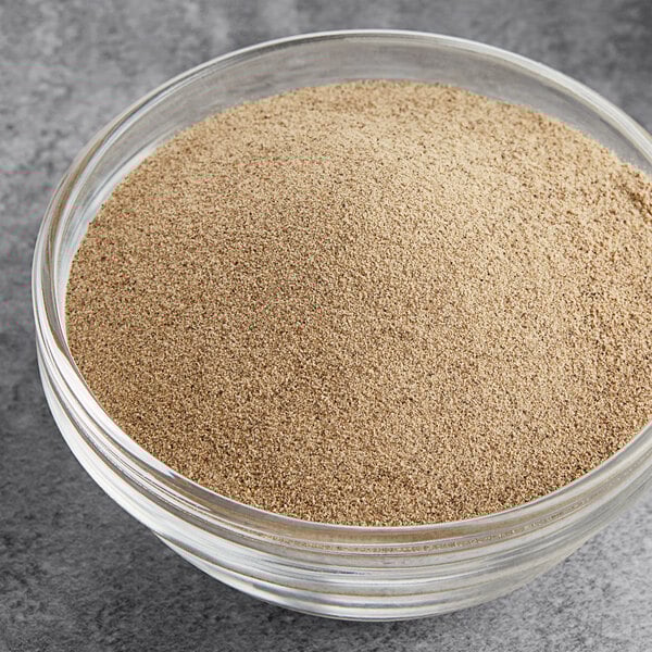 A bowl of fine ground white pepper on a grey surface.