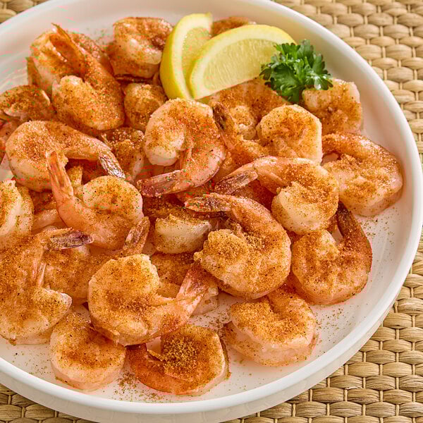 A plate of shrimp with Hometown Provisions Seafood Spice Blend and lemon wedges with a lemon slice.