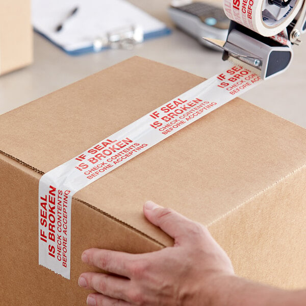 A person's hand using Tape Logic carton sealer tape to seal a box.