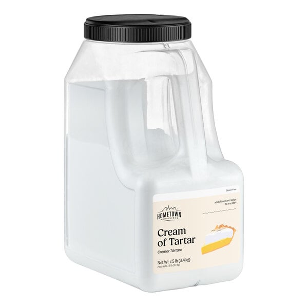 A large clear plastic container with a black screw-on lid, labeled 'Cream of Tartar' and featuring an image of a pie slice on the front.