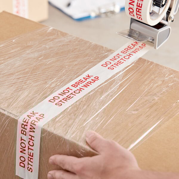 A person using Tape Logic "Do Not Break Stretch Wrap" to seal a box.