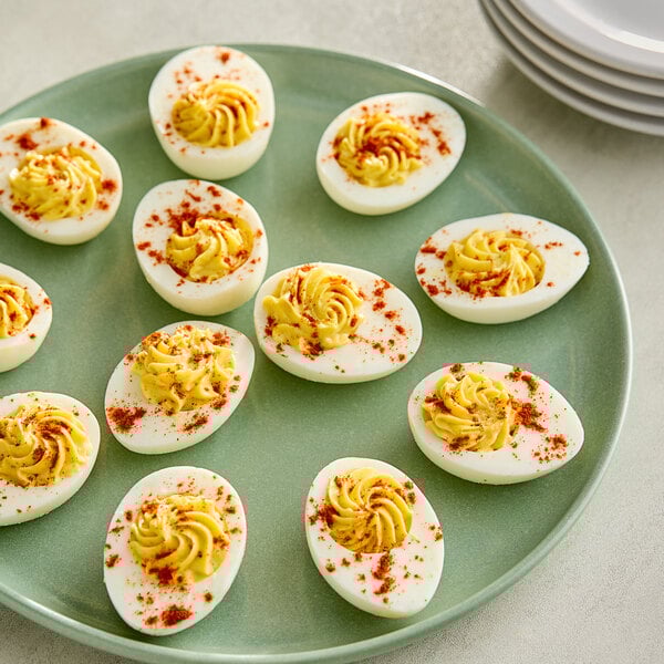 A plate of deviled eggs topped with red paprika.