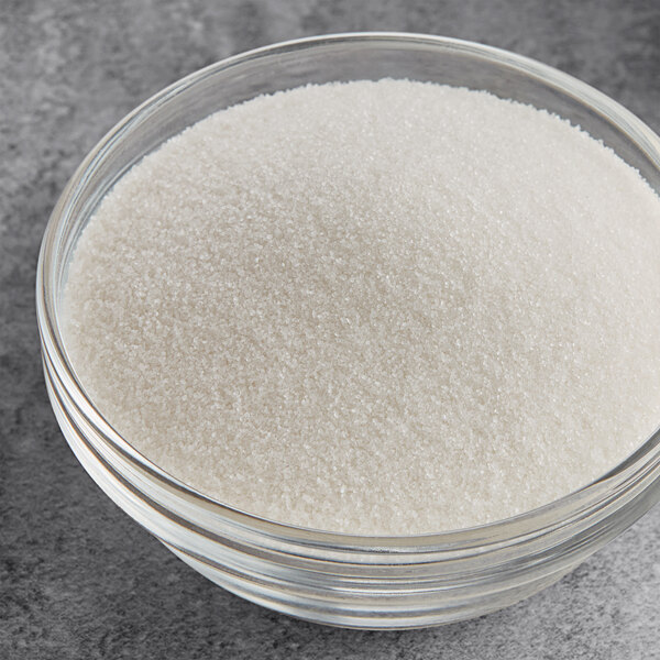 A clear glass bowl filled with fine white citric acid granules.