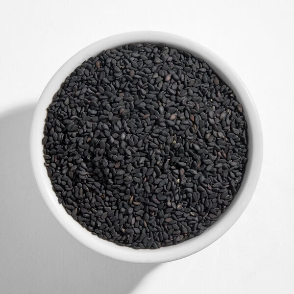 A white bowl filled with black sesame seeds.