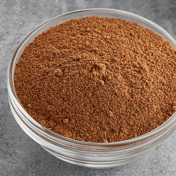 A white bowl of ground nutmeg on a table.