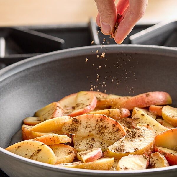 A person pouring Hometown Provisions Ground Allspice into a bowl of food.