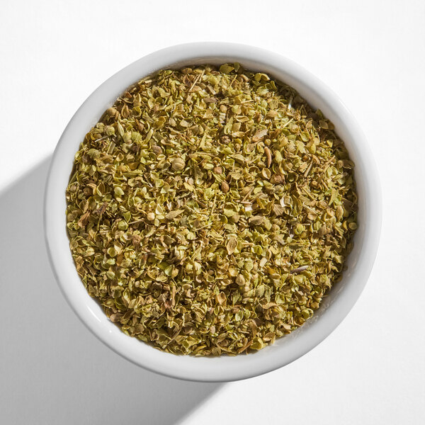 A white bowl filled with dried oregano leaves.