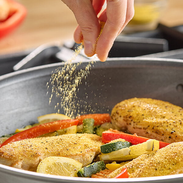 A person sprinkling Hometown Provisions Lemon Pepper on food in a pan.