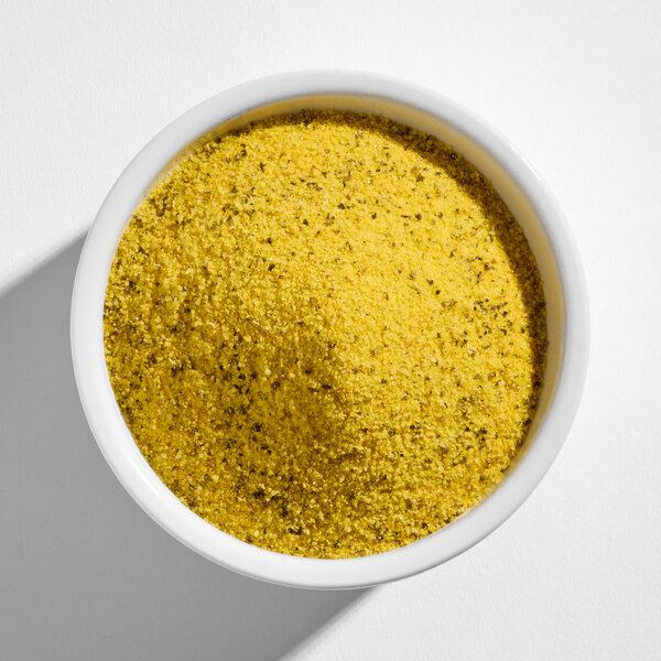 A white bowl filled with a yellow, coarse, and speckled seasoning blend.