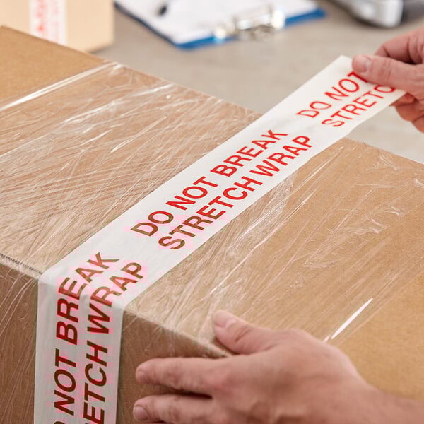 A person using Tape Logic "Do Not Break Stretch Wrap" tape to seal a box.