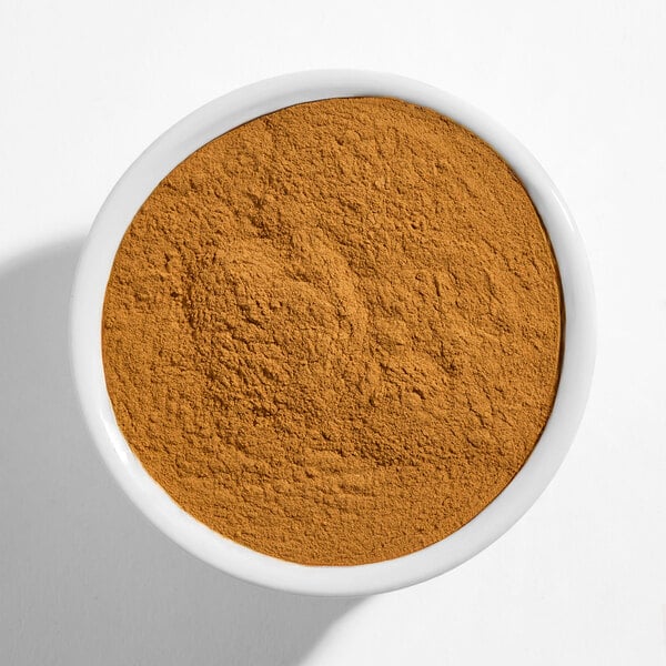 A white bowl filled with ground cinnamon powder.