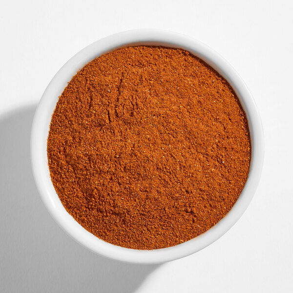 A white bowl filled with reddish-brown chipotle powder.