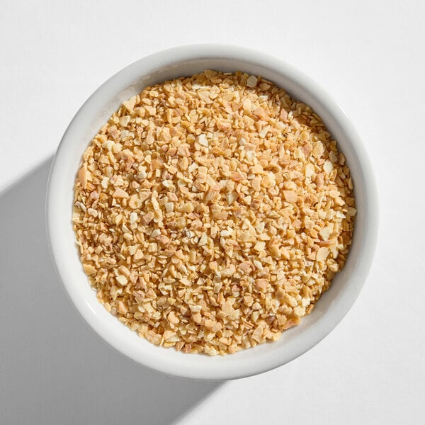 A white bowl filled with dried minced garlic pieces.