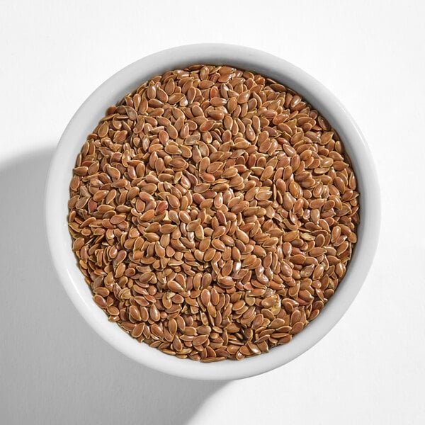A white bowl filled with brown flax seeds.