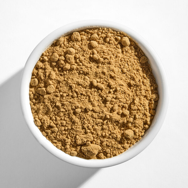 A white bowl filled with light brown ground ginger powder.