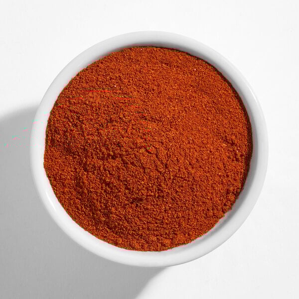 A white bowl filled with finely ground red smoked paprika powder.
