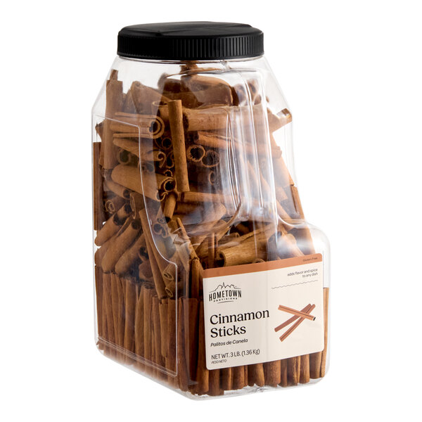 A large clear plastic container filled with cinnamon sticks and sealed with a black screw-on lid.