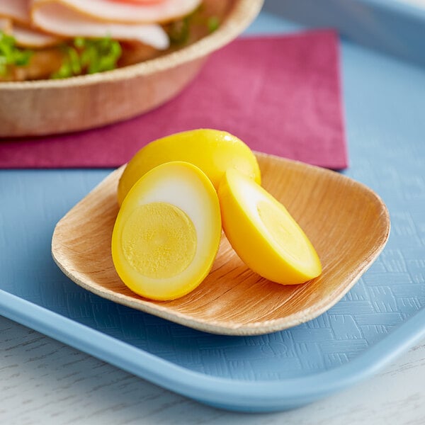 A wooden spoon with sliced yellow pickled hard boiled eggs on it.