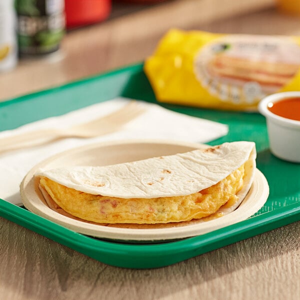 A green tray with a tortilla omelet wrap on a white surface.