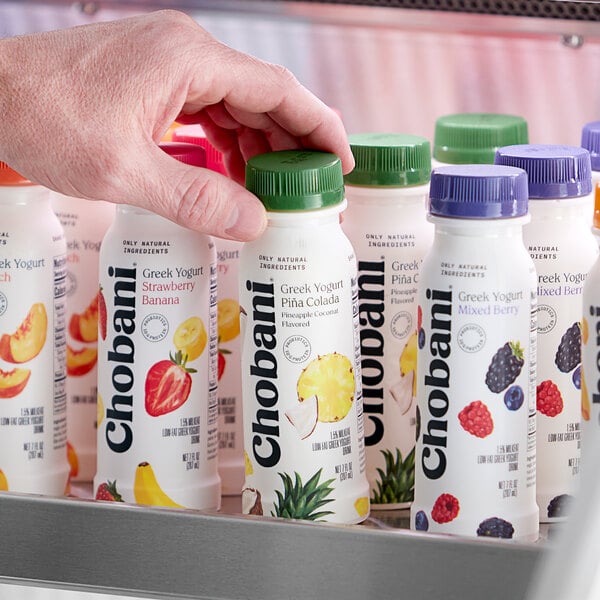 A hand holding a Chobani Pina Colada Greek yogurt drink bottle.