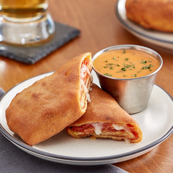 A Pizzeria Uno pepperoni calzone on a plate with pizza sauce.