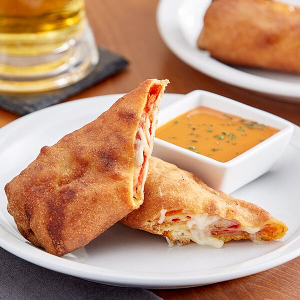 A white plate with two brown Italian meat calzones.