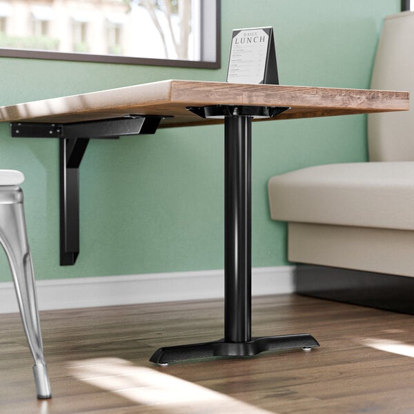 A Lancaster Table & Seating cast iron end column table base on a table in a restaurant dining area.