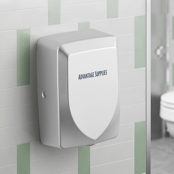 A silver automatic hand dryer mounted on a tiled restroom wall.