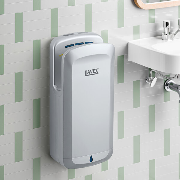A silver automatic vertical hand dryer with HEPA filtration mounted on a bathroom wall.