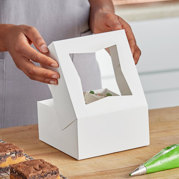 A woman holding a white Southern Champion Bakery Box with a window.