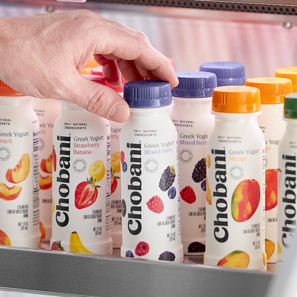 A hand holding a plastic bottle of Chobani Low-Fat Mixed Berry Greek Yogurt Drink with a purple label.