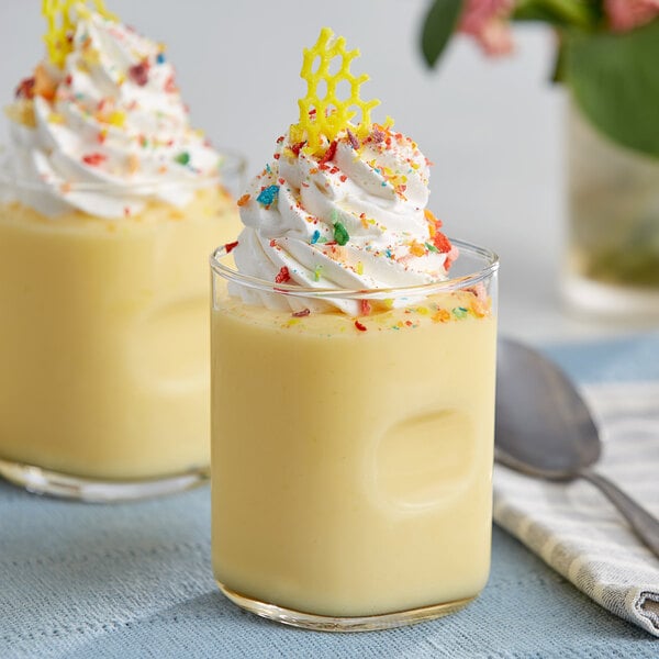 Two glasses of vanilla pudding with whipped cream and sprinkles.