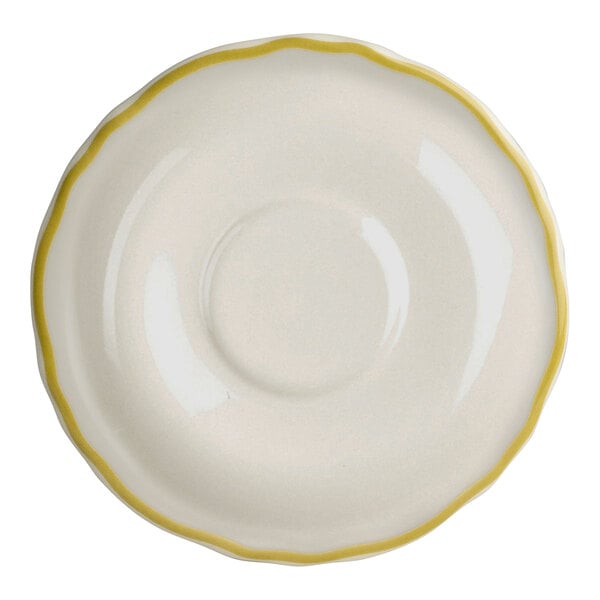 A close-up of a Homer Laughlin white china saucer with a yellow scalloped edge.