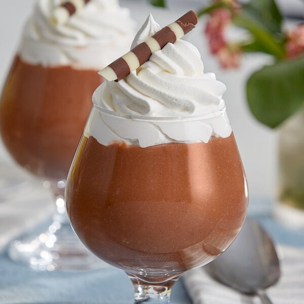 A close-up of two glasses of chocolate pudding with whipped cream.