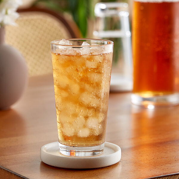 A glass of Twinings black iced tea with ice on a coaster.