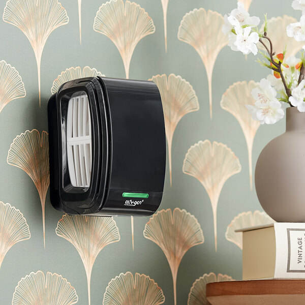 A black wall-mounted Oxy-Gen air freshener system.
