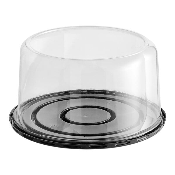 A clear plastic cake display container with a black scalloped lid.