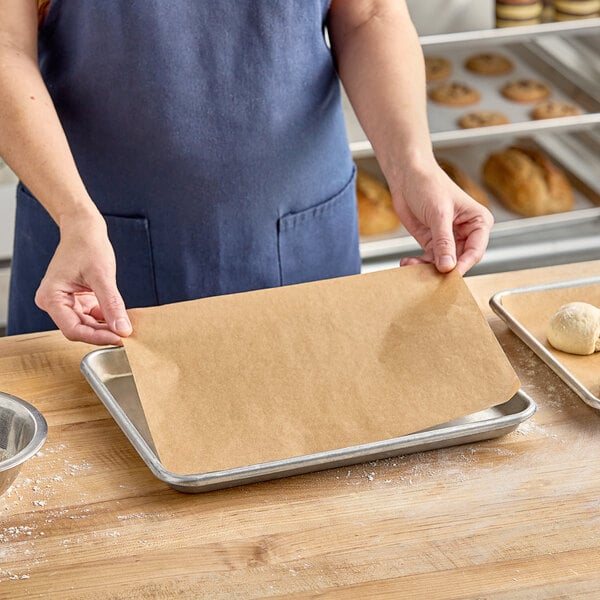 A woman using a Baker's Lane unbleached parchment paper sheet to line a baking tray.