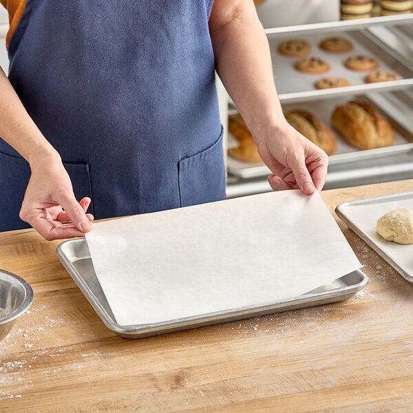 A woman in a blue apron using a Baker's Lane parchment paper sheet to make dough.