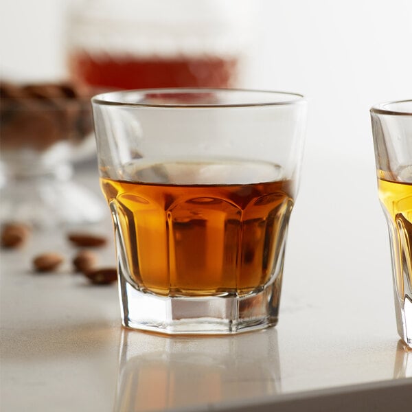 Two Libbey Gibraltar tall rocks glasses filled with brown liquid on a table.