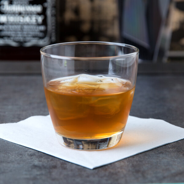A Libbey Embassy Rocks glass of whiskey with ice on a table.