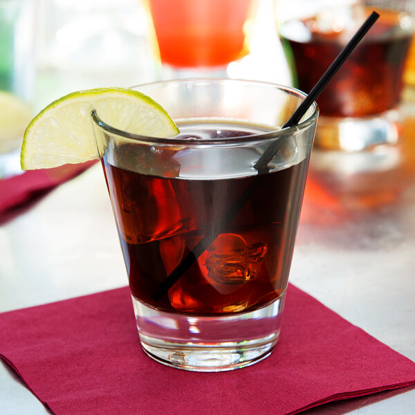 A Libbey rocks glass with a drink, a straw, and a lime slice.