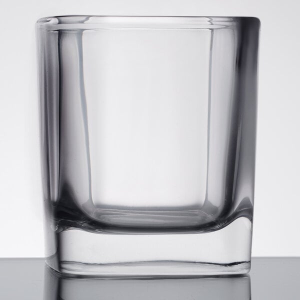 A close up of a Libbey clear glass with a square bottom.
