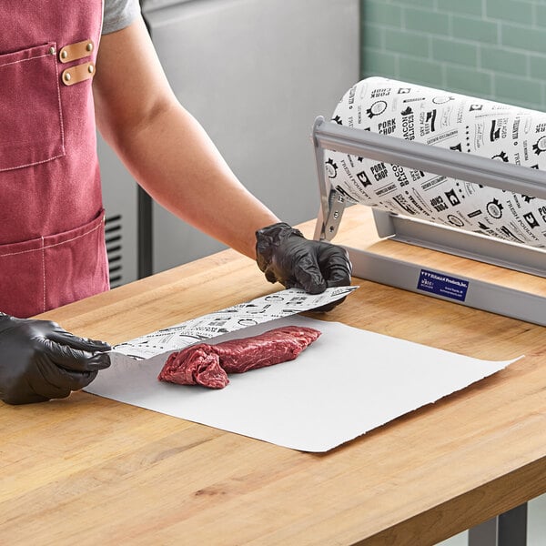 A person in black gloves and a red apron cutting meat on Choice barbecue print butcher paper.