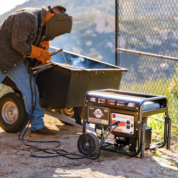 A man welding a metal object to a Tomahawk portable generator.