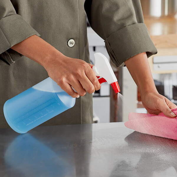 A person using a red Lavex spray bottle to clean a table.