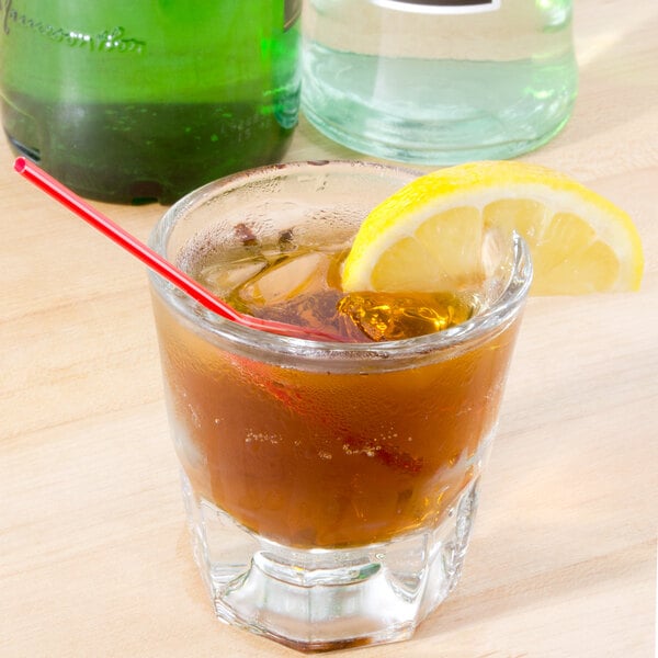A Libbey rocks glass of iced tea with a lemon slice and a straw.
